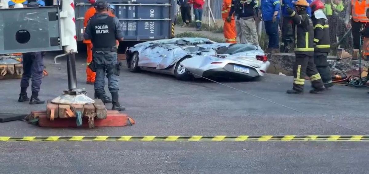 O carro ficou completamente amassado após ter sido esmagado pelo contêiner da carreta (Foto: Reprodução)